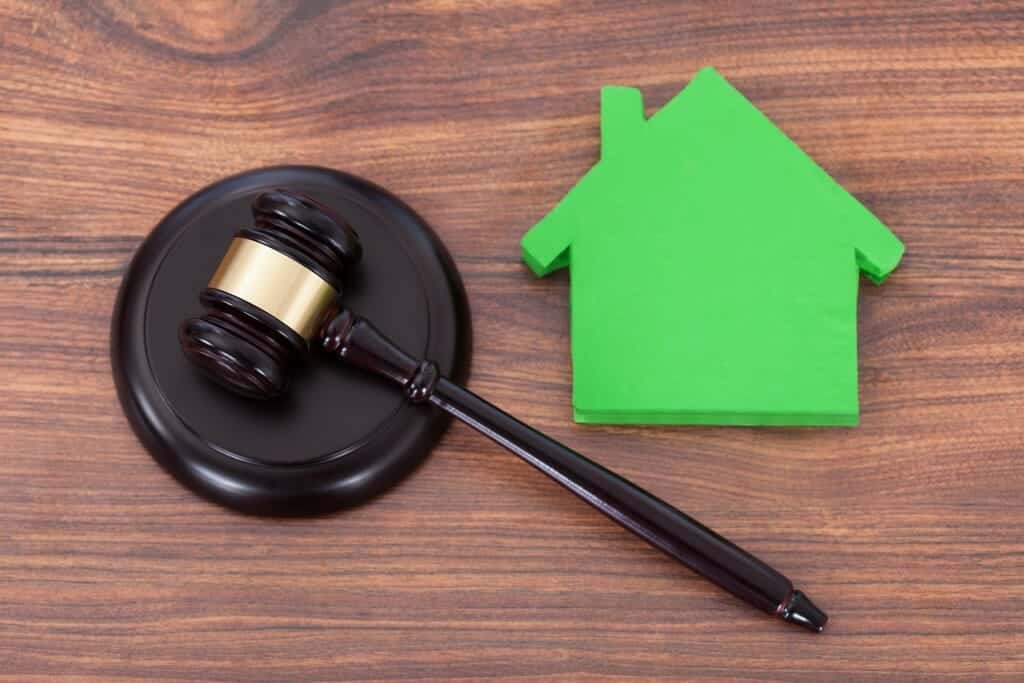 Judge's gavel next to a green cut-out of a house.
