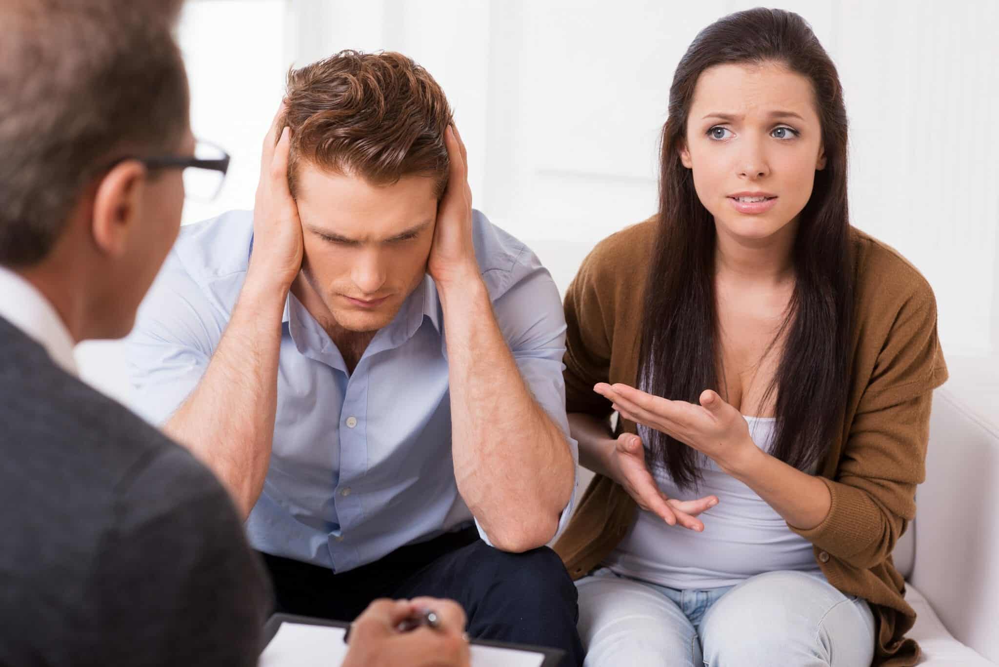 Frustrated couple going through marriage counseling with a therapist.