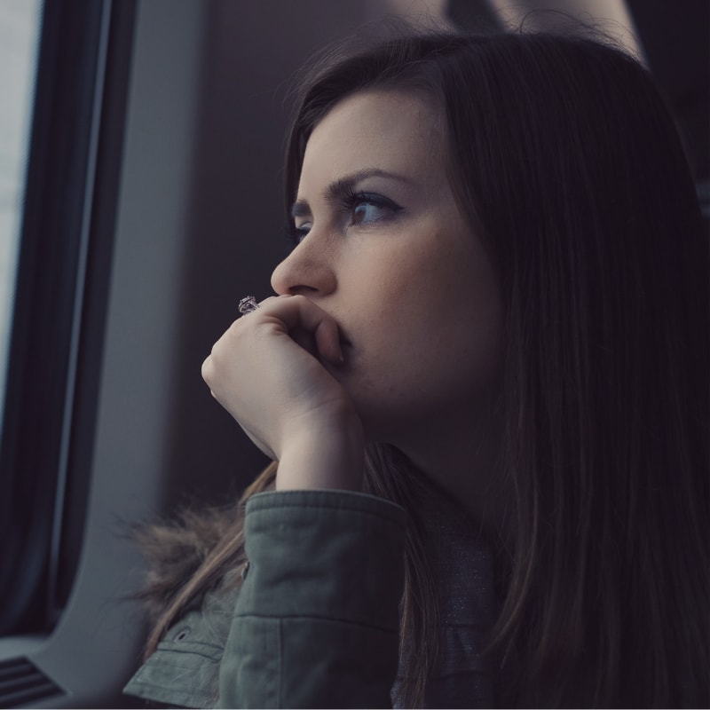 Sad woman looking left out the window of a train