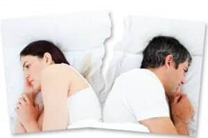 Man and woman sleeping in the same bed with their backs to each other.