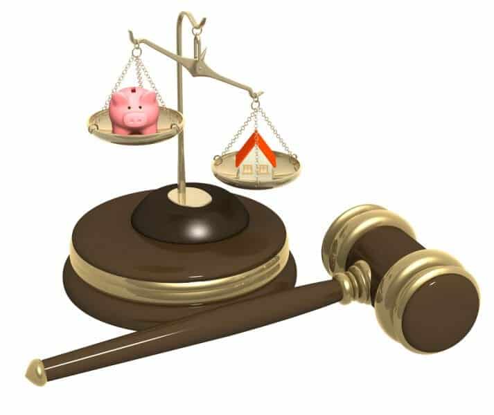 Scales of Justice weighing a piggy bank and a house with a gavel near by.