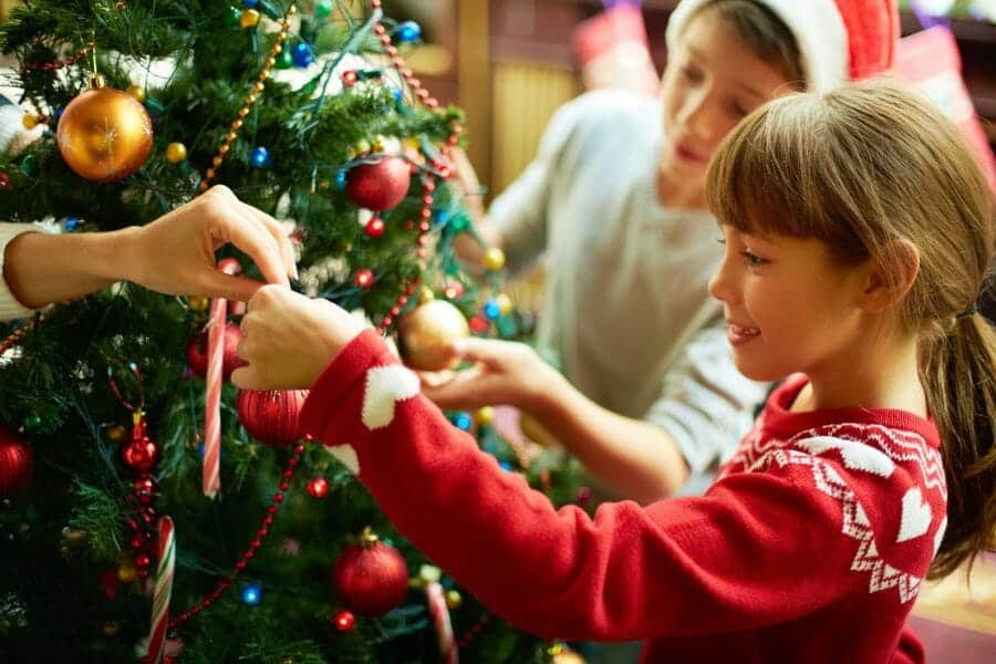 Happy children decorate a Christmas tree.