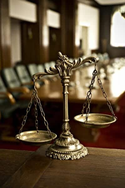 Close up of unbalanced scales of justice with a court room in the background