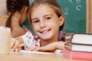 Smiling young girl with a good parenting plan sitting in school.