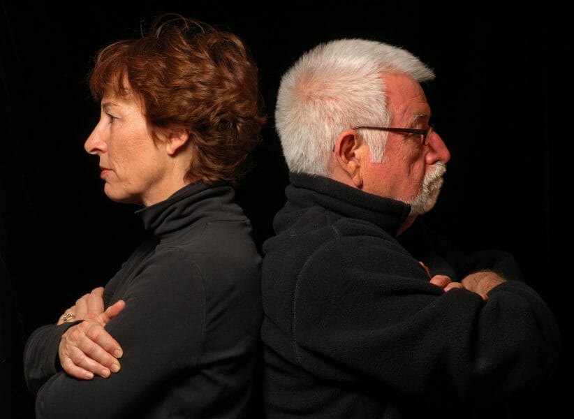 Attractive, angry senior couple sitting back-to-back.