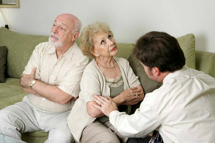 Senior couple arguing with their adult child of divorce mediating between them.
