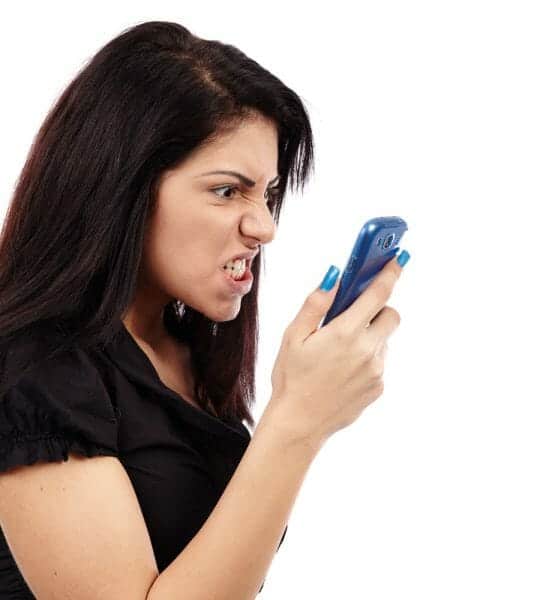 Angry woman making a face at her cell phone.