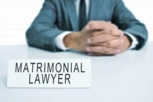 Attorney sitting at a table with a sign "Matrimonial Lawyer." Should you change attorneys during your divorce?