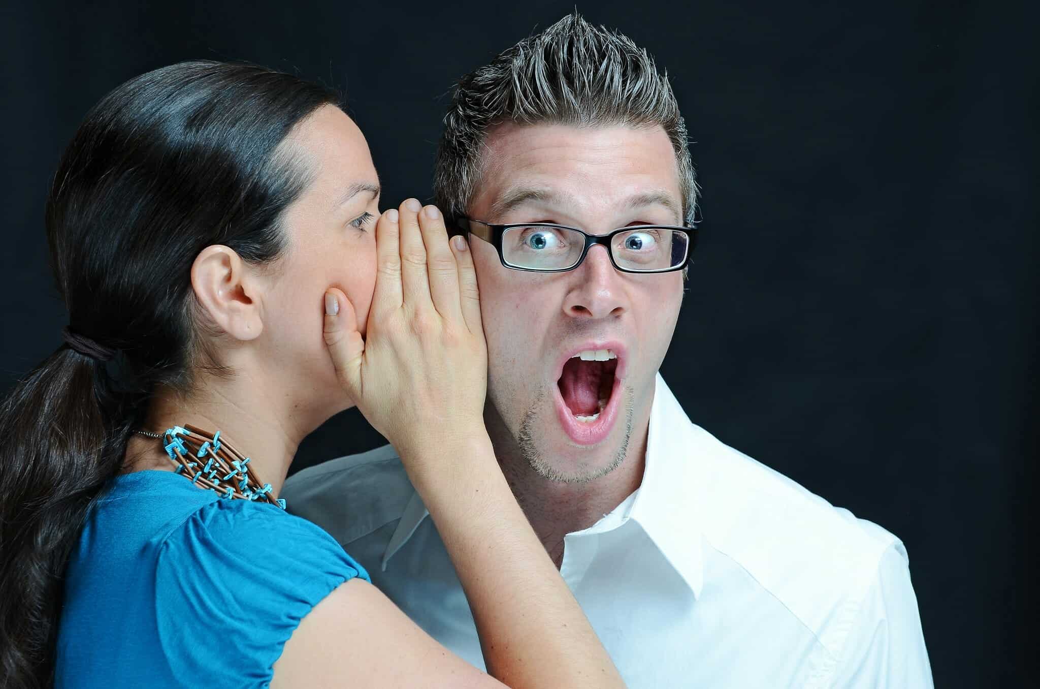 Woman whispers into a surprised man's ear. He can't believe what she says.