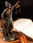 Bronze lady justice statute next to open law book