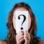 woman holding paper with question mark in front of her face