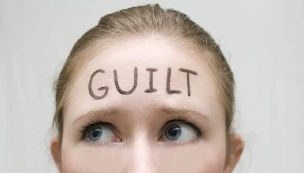 Woman with "Guilt" written on her forehead.