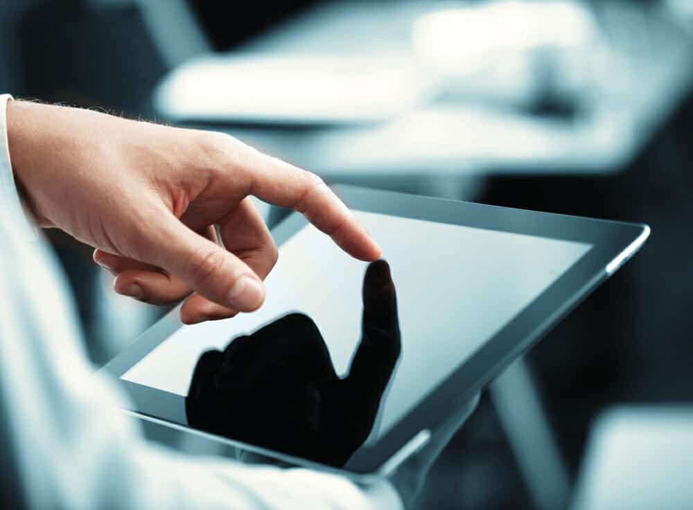 Hand with finger on a tablet computer.