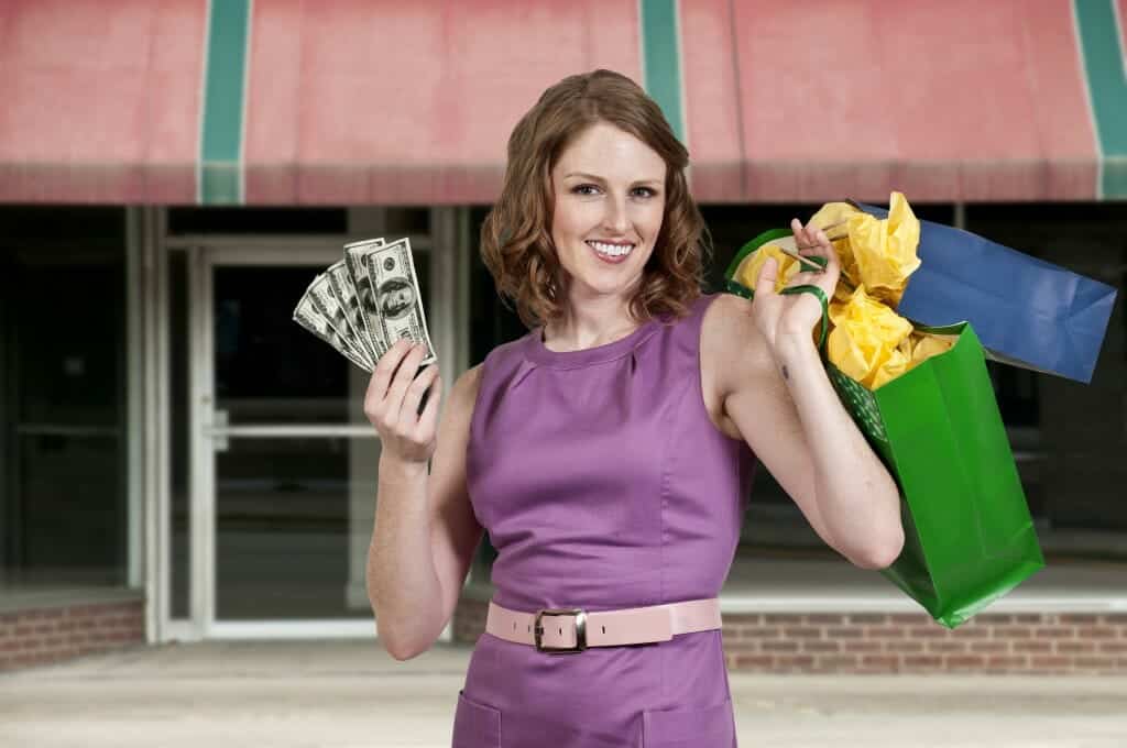 Woman Shopping, holding up money and purchases.