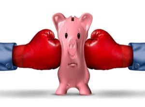 pink piggy bank getting squeezed from both sides by red boxing gloves