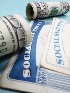 Social Security card next to rolled up $100 bills.