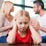 small girl covers her ears while parents argue