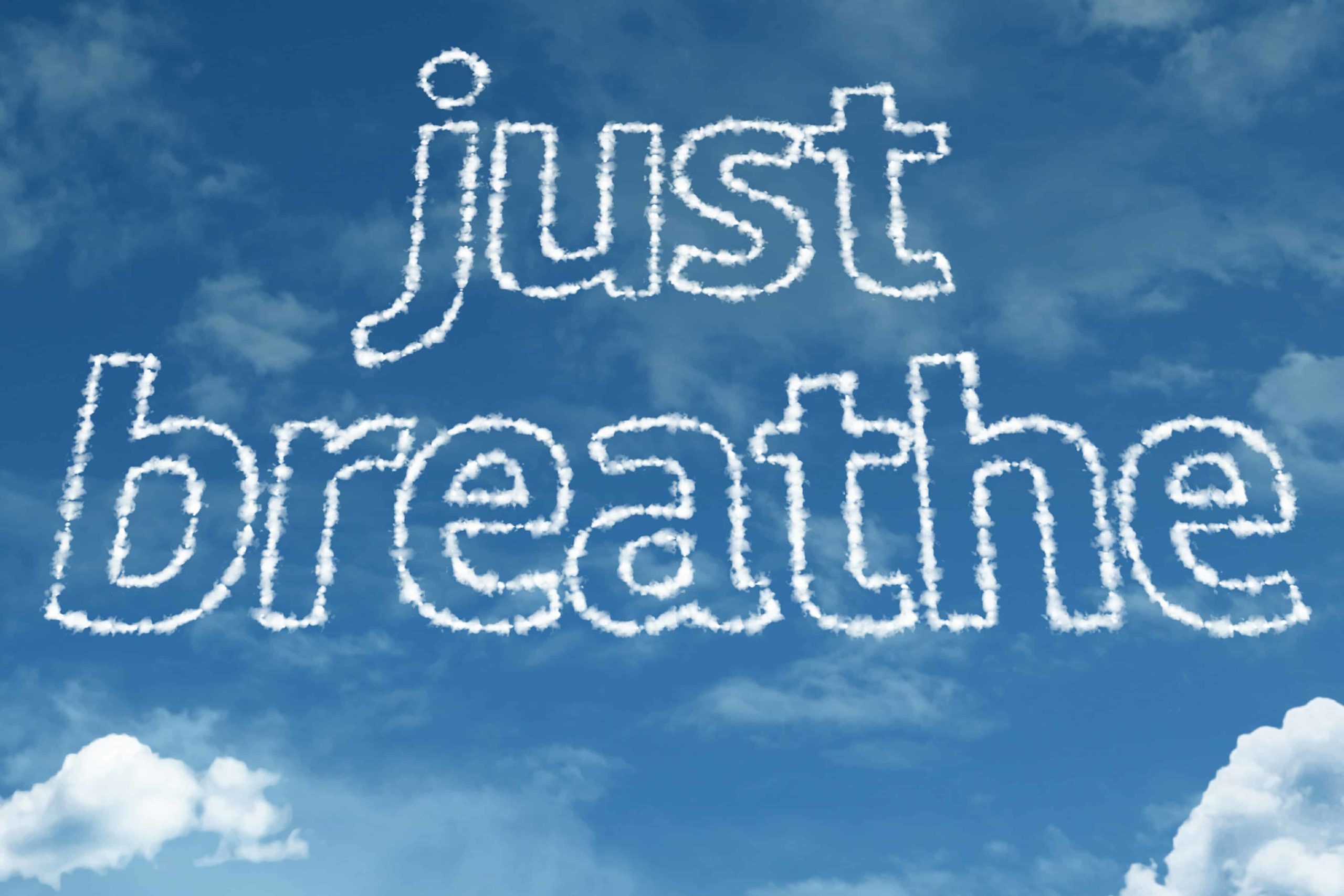 "Just breathe" written in clouds on a blue sky.