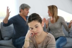 Depressed girl with parents screaming at each other in the background.