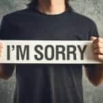 Man holding "I'm Sorry" sign in front of his chest
