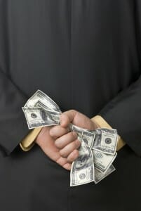 Man holding 100 dollar bills behind his back.