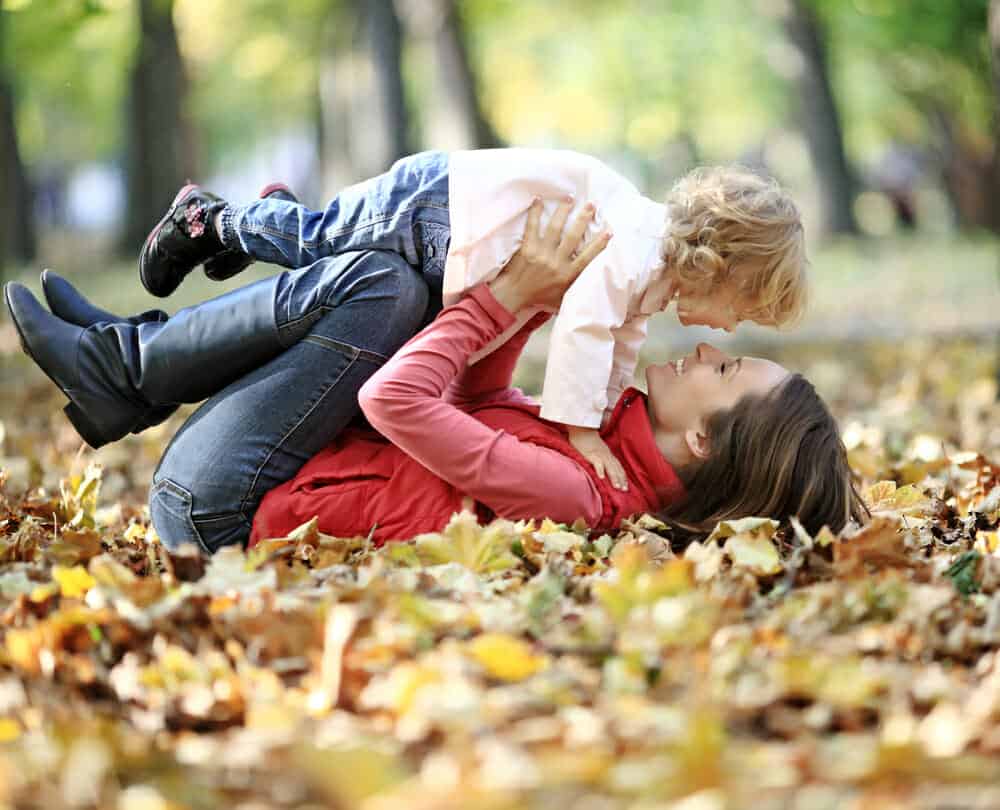 Mother playing with daughter in the leaves