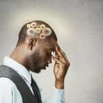 African American man holding his forehead while wheels turn inside his brain