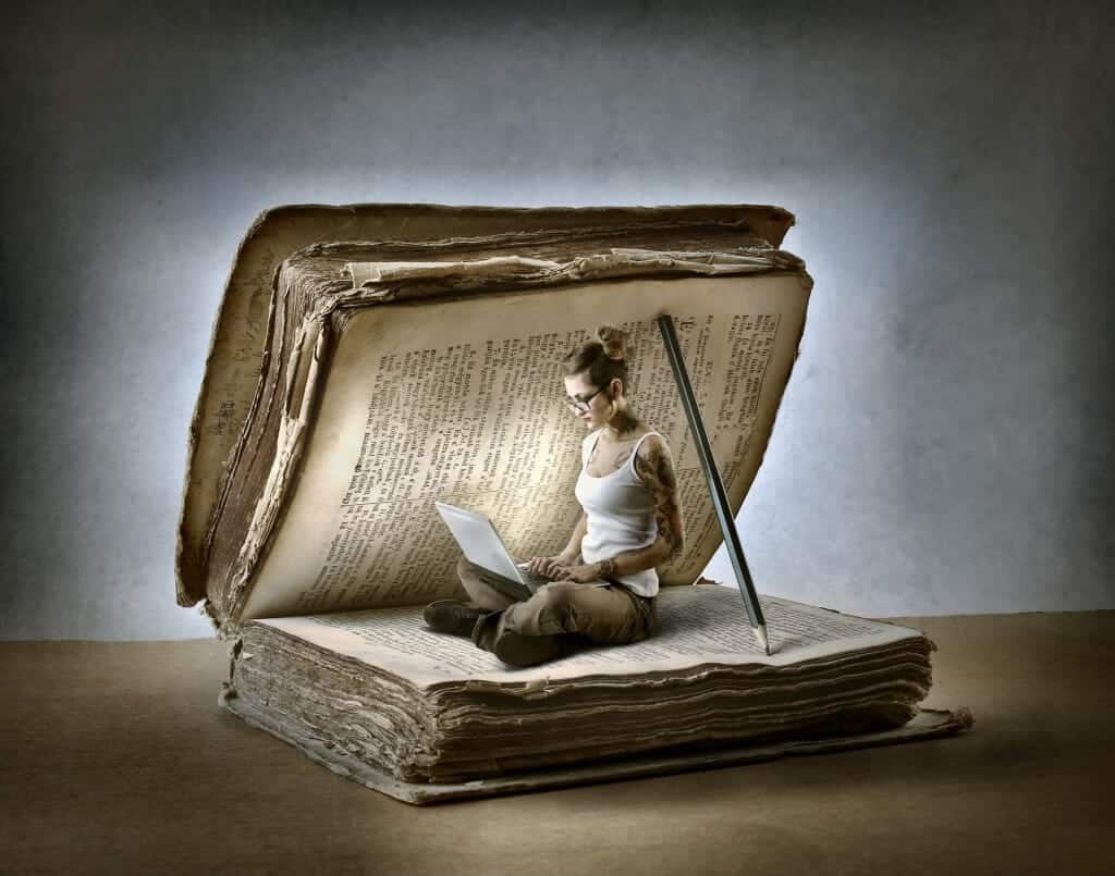 Picture of a woman reading on a laptop inside of a giant book held open by a pencil.