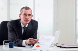 Lawyer at his desk pointing to a document.