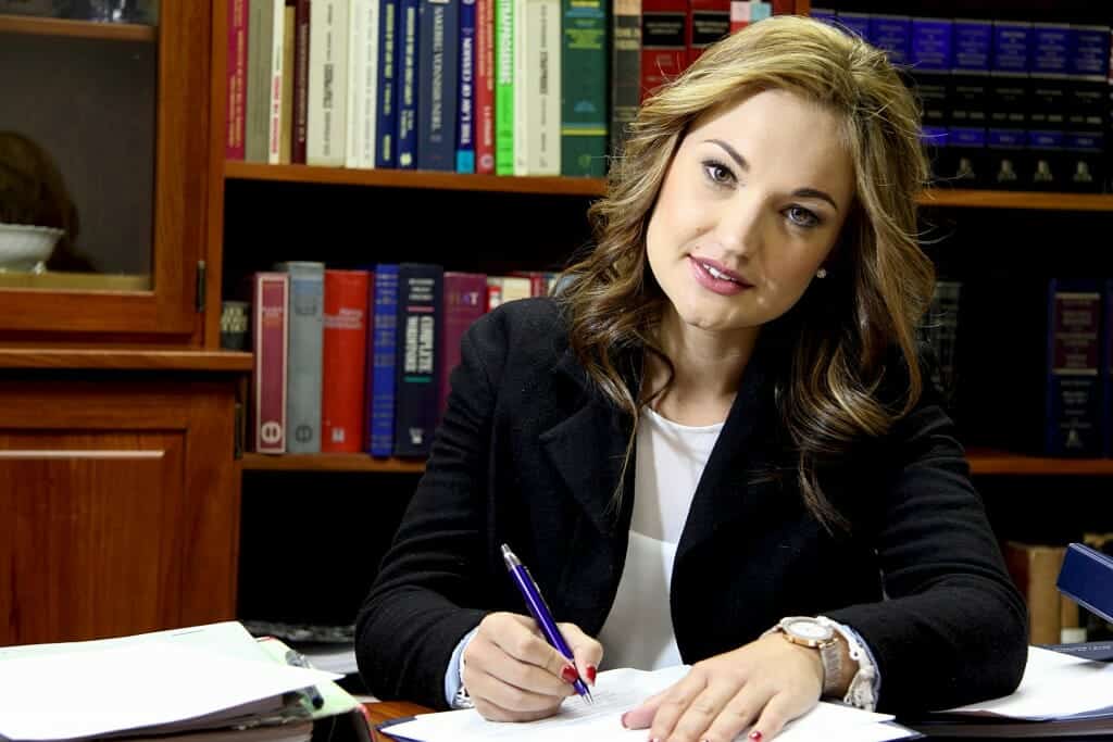 Pretty female divorce attorney taking notes in a library of law books.