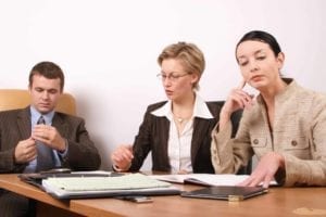 Unhappy man and woman sit at a business table with a divorce mediator.