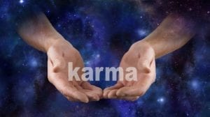 Hands on a mystical background holding the word "Karma."