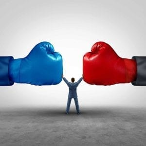 Giant Red and Blue Boxing Gloves face off, with a small man in the middle, holding them apart.