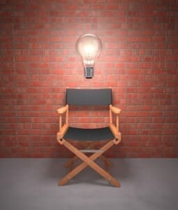 Empty director's chair against a brick wall with a giant, lit light bulb over it. signifying divorce coach is like a director