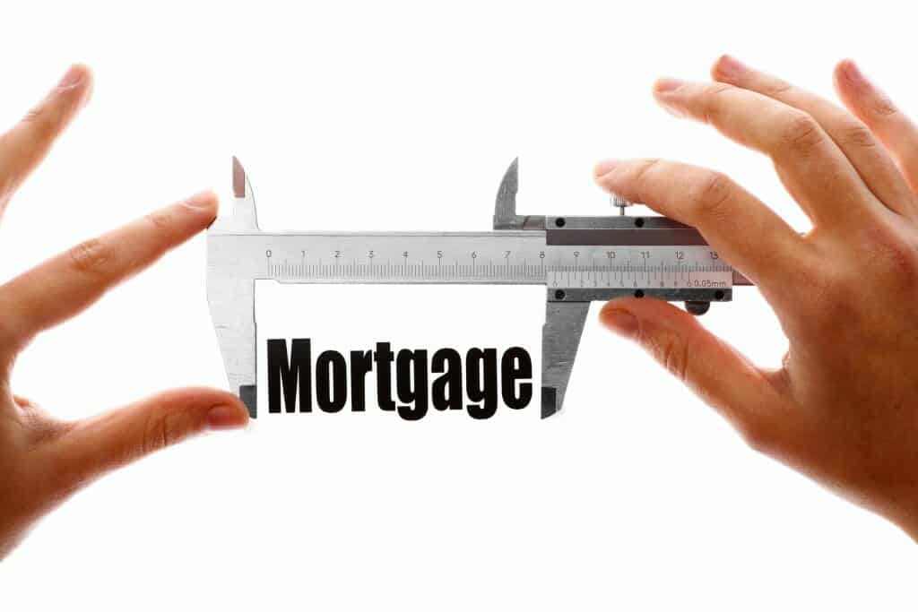 Hands with a ruler measuring the word "mortgage."