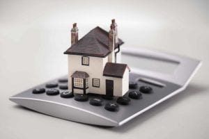 A house is expensive! Toy house sits on top of a calculator.