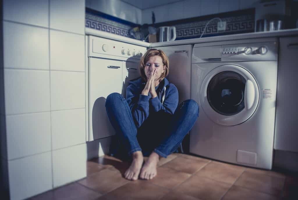 Lonely, upset woman sitting alone in laundry room.