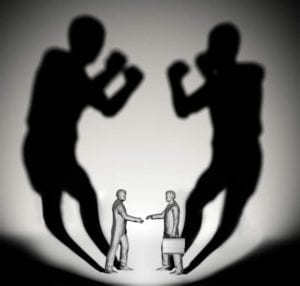 Business men shaking hands while their shadows box with each other.