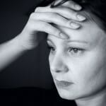 Black and white picture of a depressed woman holding her head.