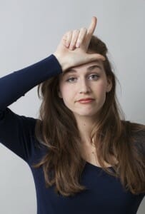 Woman experiencing divorce stigma making an "L" with her fingers at her forehead.