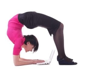 Woman doing a back bend while working on a laptop computer.