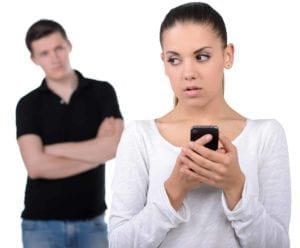 Upset man looks at guilty woman using her cell phone. He caught her cheating.
