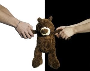 Man and woman in a custody battle pulling at arms of a teddy bear.