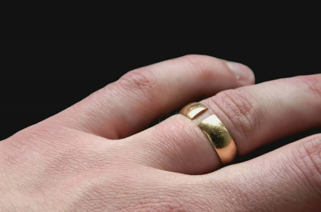 Close up of a left hand with a broken wedding ring on it, signifying Legal Separation