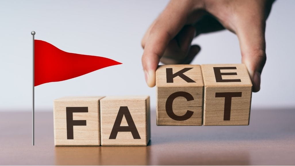 The word "fake" spelled out in blocks. The last 2 letters are being replaced with "ct". There is a red flag on the side