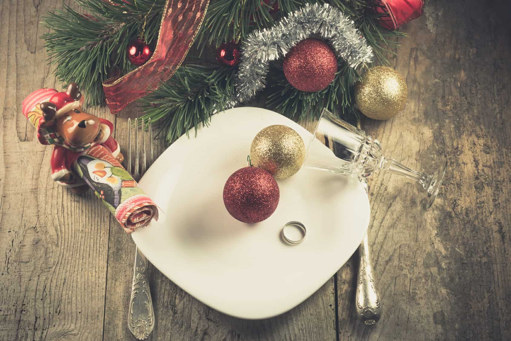Christmas divorce shown by decorations on an empty dinner plate with a wedding ring on it