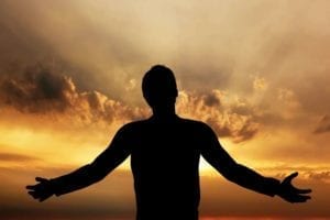 Silhouette of a grateful man at sunrise.