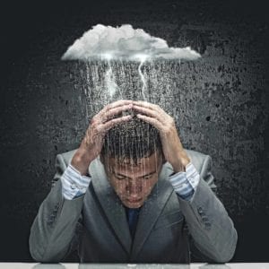 Young businessman holding his head and thinking, "divorce sucks!,"while a small cloud rains on him.