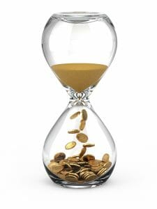 Hourglass with sands of time turning into gold coins signifying time and money.