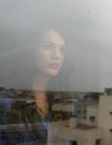 Beautiful woman in a bad marriage staring out through a rainy window